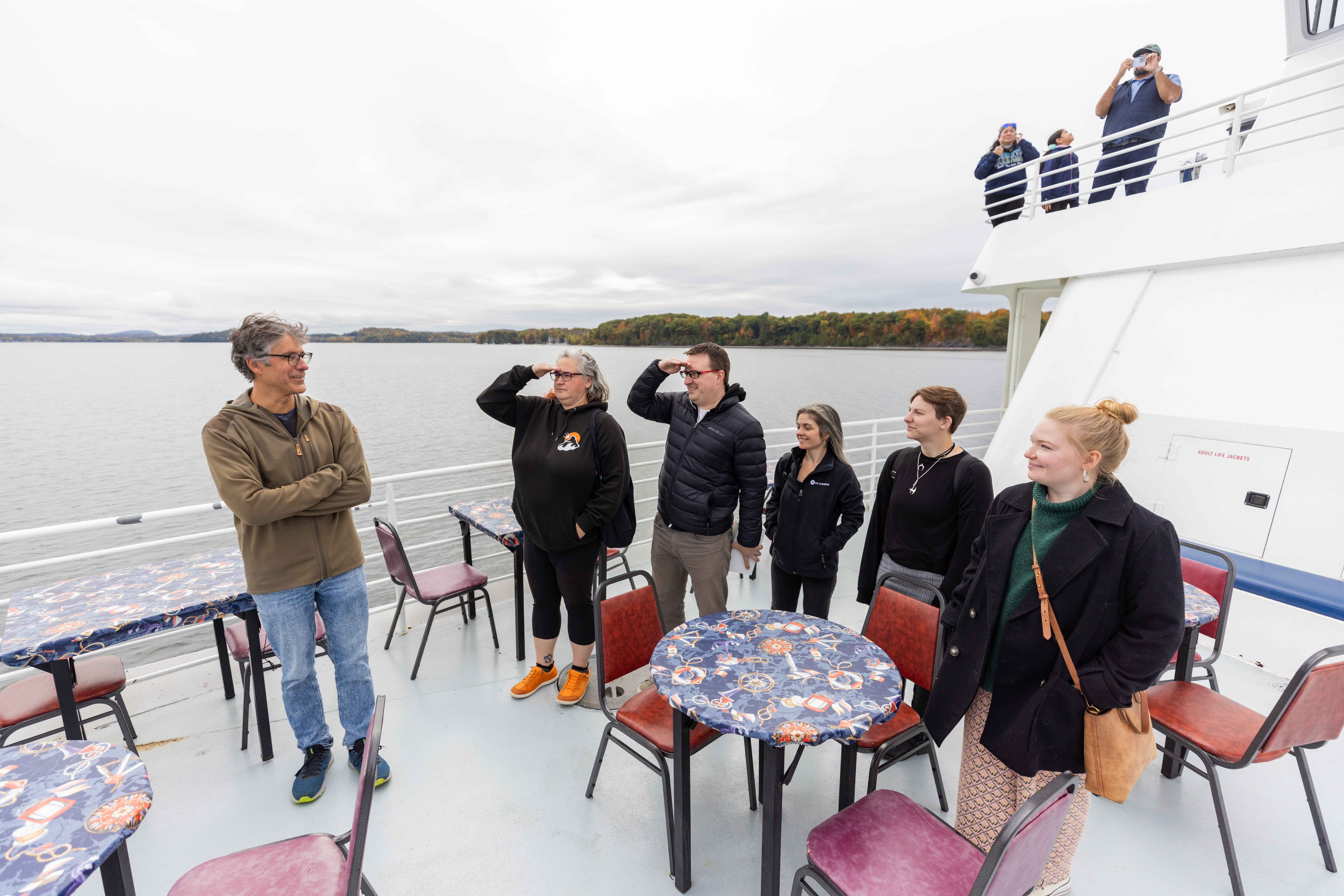 Group of people on a boat looking out at the water with a cloudy sky